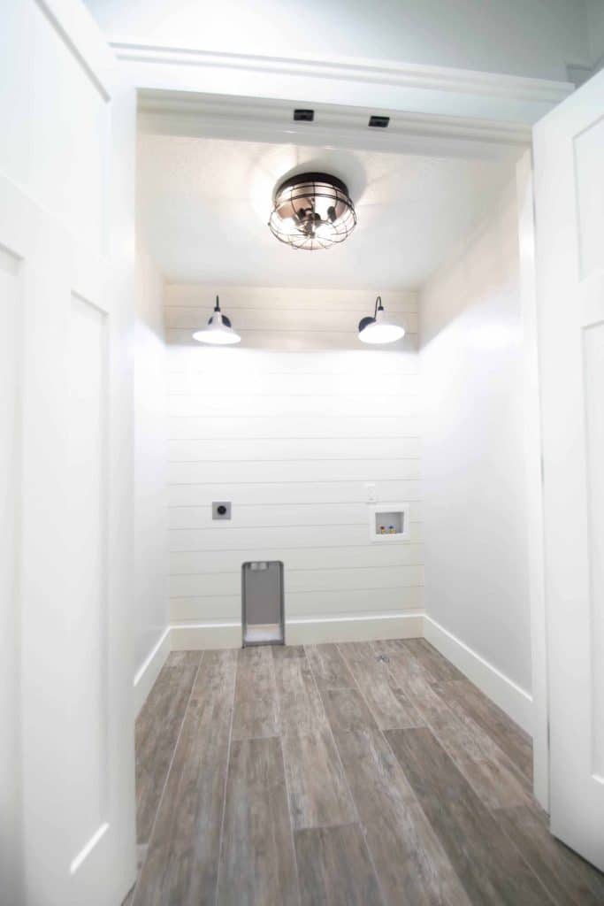 Basement laundry room with shiplap wall, barn sconces and wood-look tile floor, Millgate Homes, Utah County